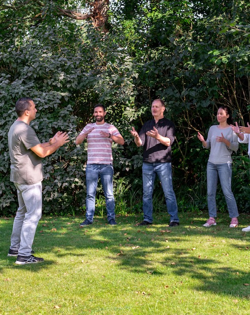 Een team doet een oefening in de tuin van Doyo tijdens een teamdag op maat in Lage Zwaluwe