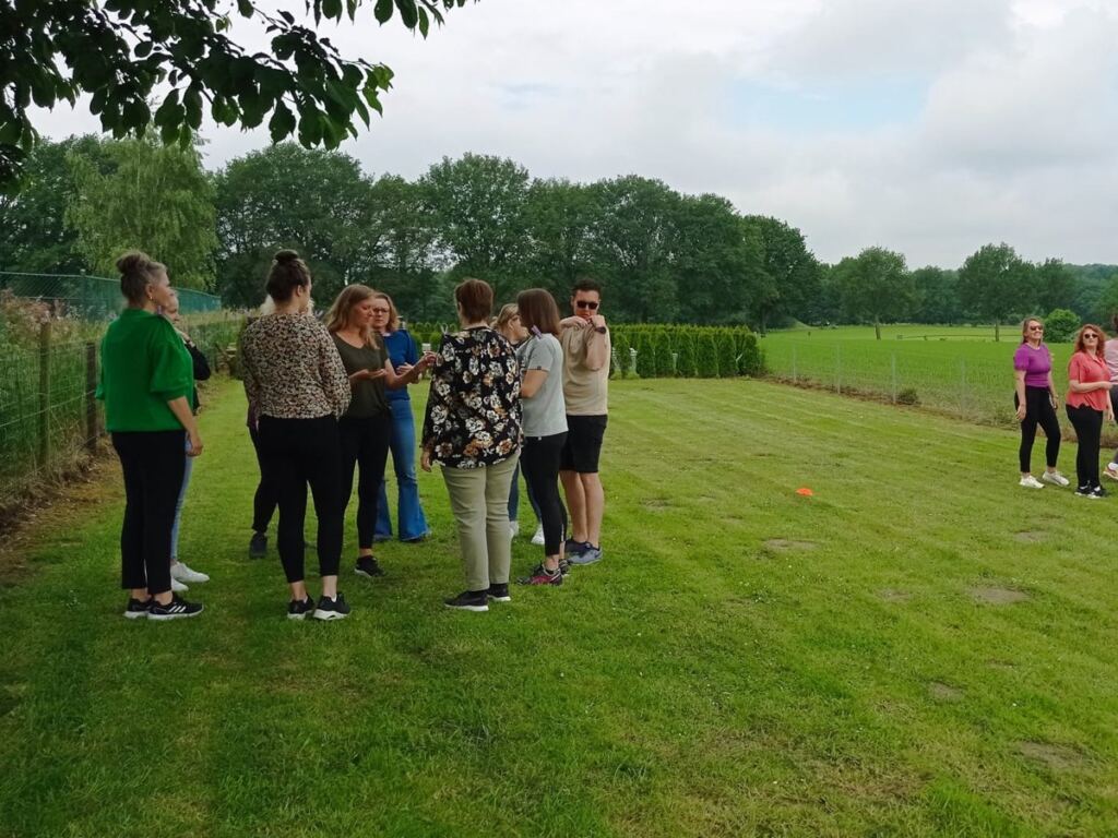 Teamleden doen samen een oefening buiten tijdens een teamtraining op hun eigen locatie