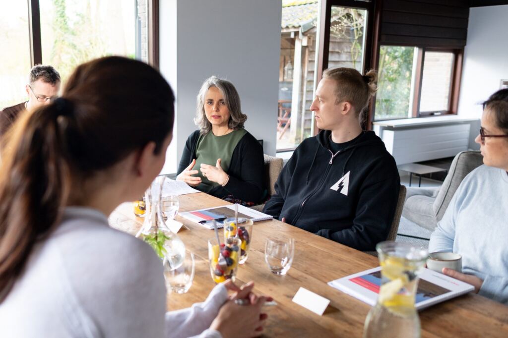 Een team in gesprek aan de grote houten tafel bij Doyo